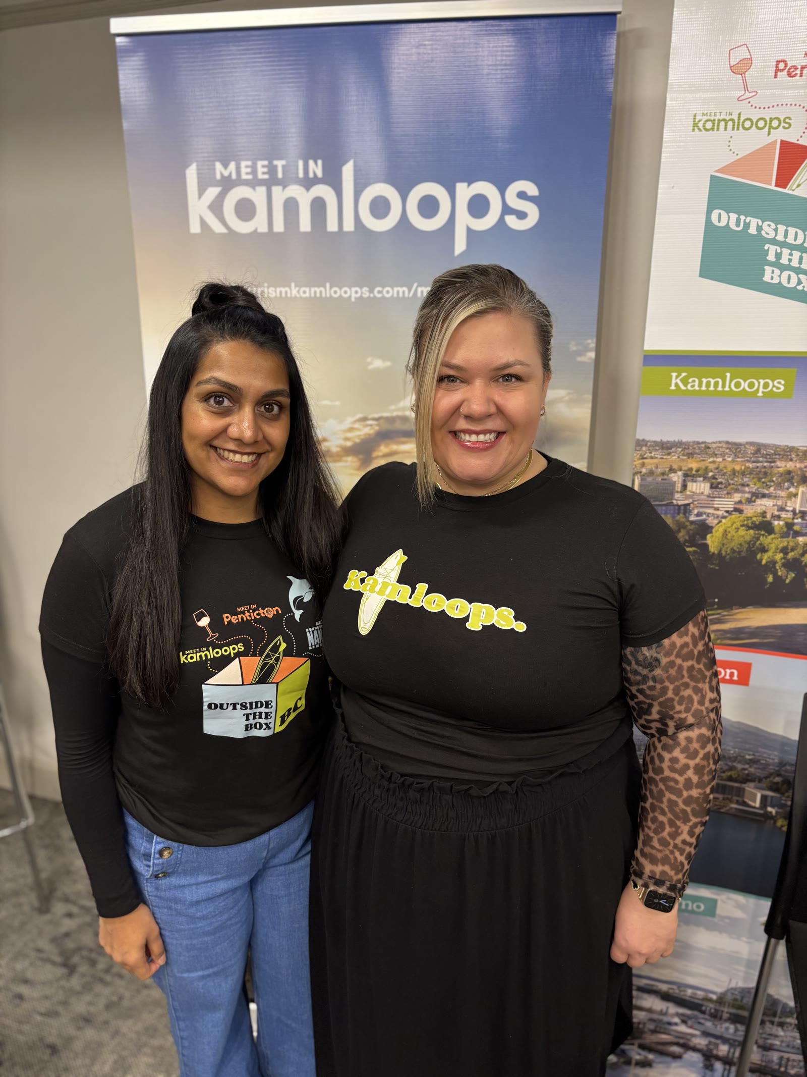 Archana and Roxanne in front of Meet in Kamloops and Outside the Box BC displays
